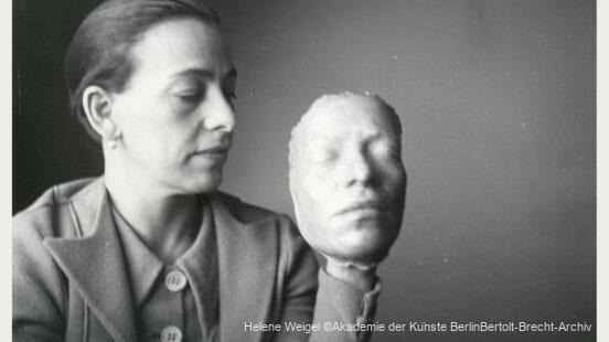 Helene Weigel mit Maskenentwurf ca. 1939 im Schwedischen Exil. Eine Frau mit zurückgebundenen Haaren hält eine plastische Gesichtsmaske, die an ein menschliches Gesicht erinnert, in ihrer Hand.