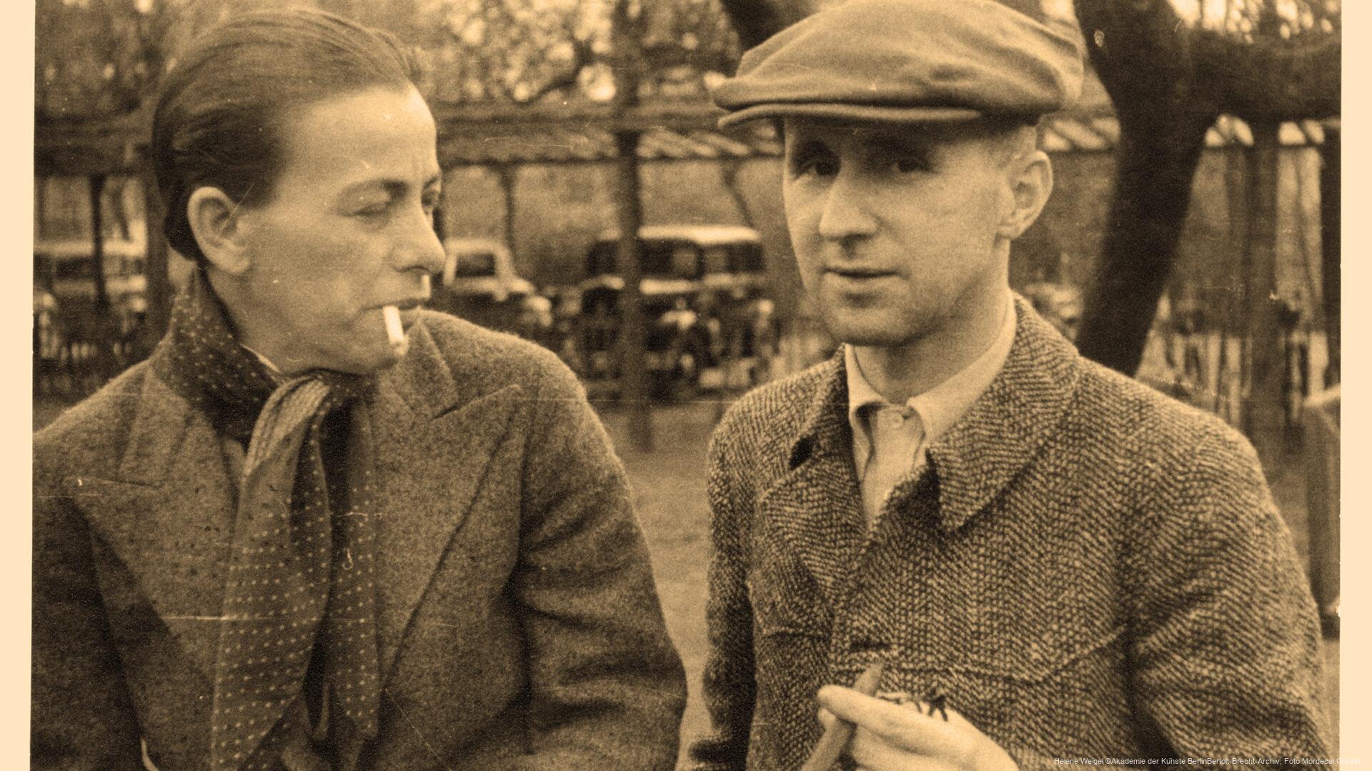 Helene Weigel und Bertolt Brecht 1936 in Dänemark. Eine Frau mit Zigarette und ein Mann mit Schiebermütze stehen nebeneinander im Freien, beide in warmer Kleidung.