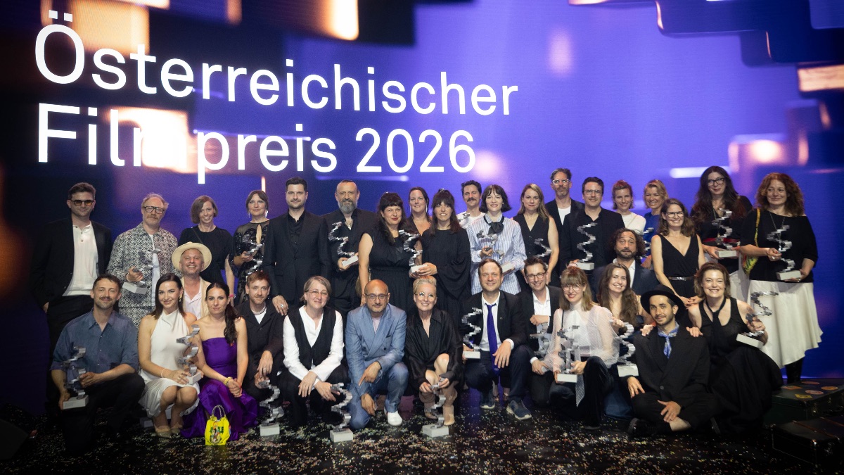 Große Gruppe von Personen mit Trophäen auf einer Bühne vor dem Schriftzug „Österreichischer Filmpreis 2026“.