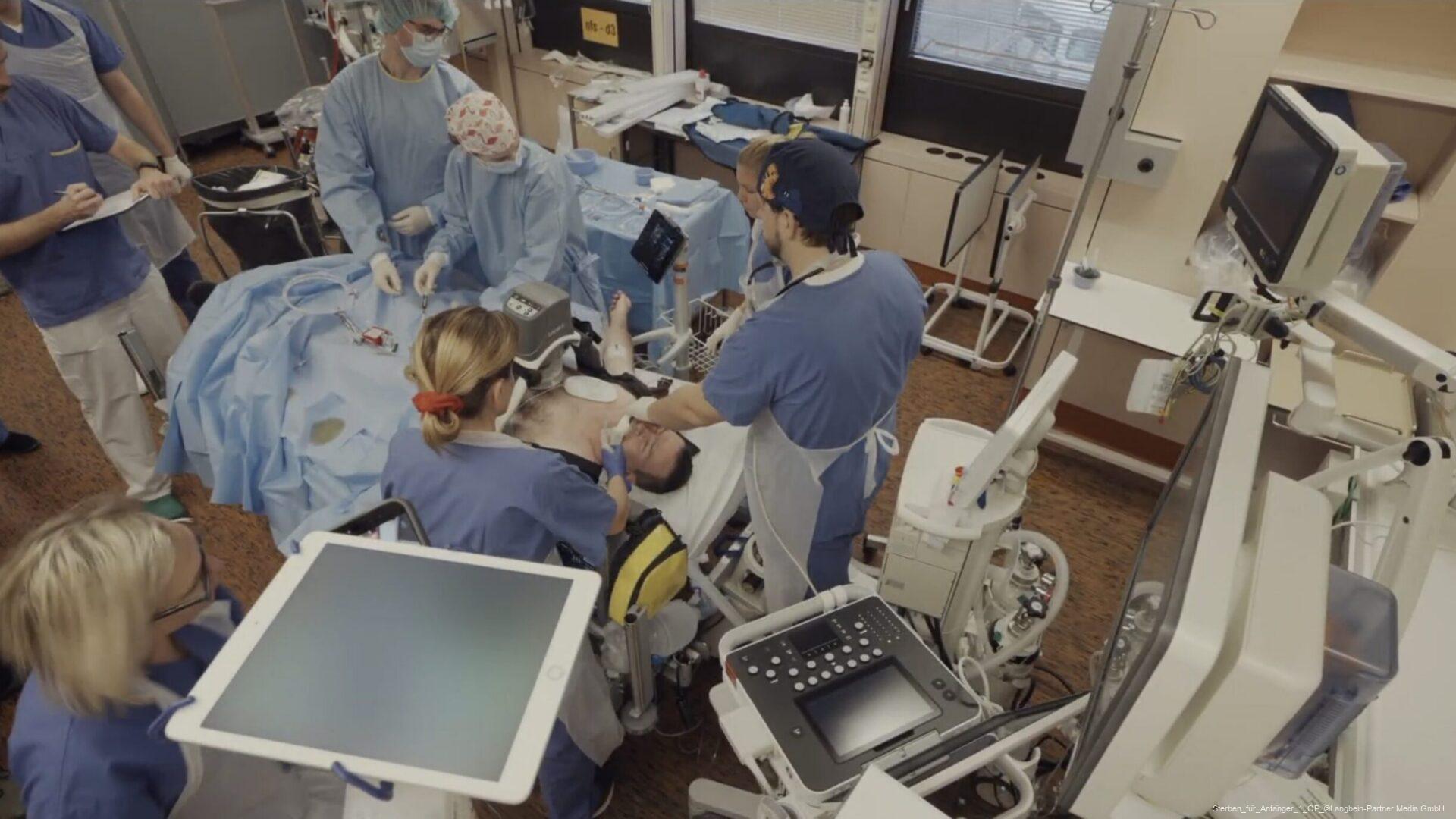 Medizinisches Team behandelt einen Patienten in einem OP-Saal mit Monitoren und Geräten