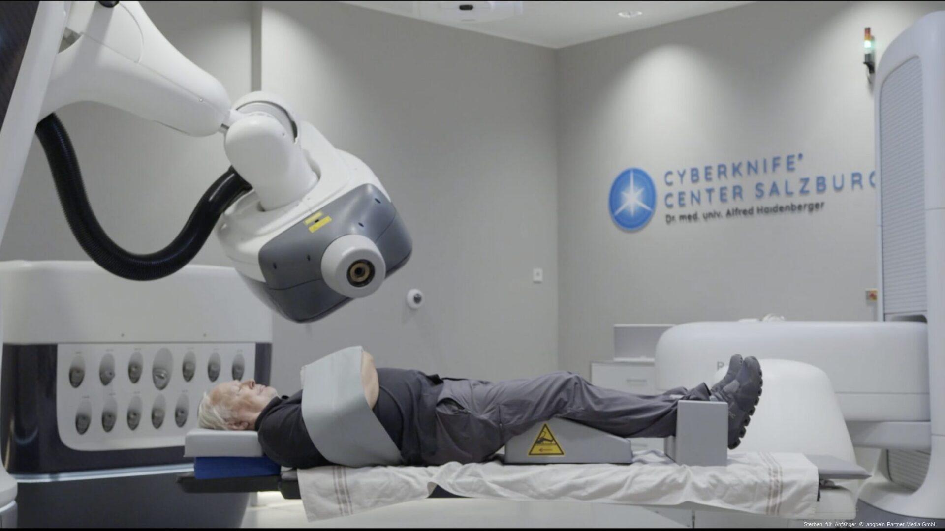 Patient liegt in einem Behandlungsraum unter einem CyberKnife-Roboterarm